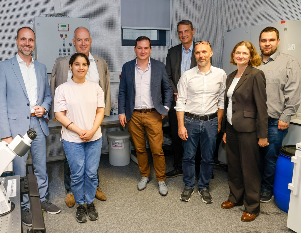 Wissenschaftsminister Clemens Hoch (l.), JGU-Präsident Prof. Dr. Georg Krausch (3.v.l.) und JGU-Vizepräsident Prof. Dr. Stefan Müller-Stach (5.v.l.) mit Wissenschaftler*innen des Exzellenzprojekts CoM2Life (Foto: Stefan F. Sämmer)