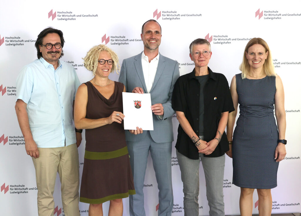 Wissenschaftsminister Clemens Hoch (Mitte) übergibt den Förderbescheid für das Projekt "PRO.SOZIAL" an der Hochschule für Wirtschaft und Gesellschaft Ludwigshafen an die Antragstellerinnen Prof. Dr. Marion Ott (2.v.l.) und Prof. Dr. Karen Wagels (2.v.r.) im Beisein von Dekan Prof. Dr. Peter Rahn und Vizepräsidentin Prof. Dr. Edith Rüger-Muck (Foto/©: Antonia Zwicker / HWG LU)